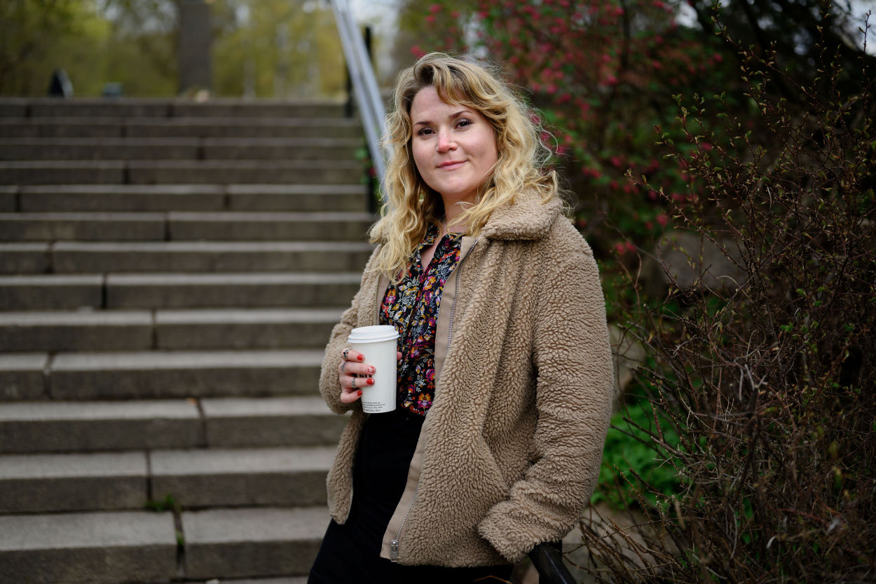 Ung kvinne står i en trapp med kaffekopp i hånden