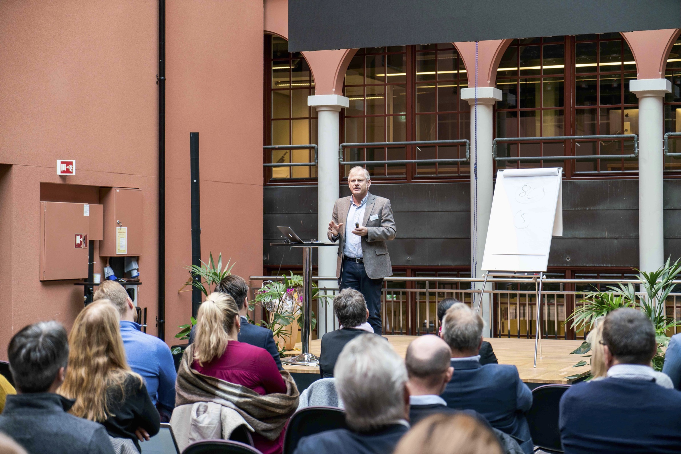 Nils Høgevold står på en scene og snakker til deltakerne på et seminar ved Kristiania