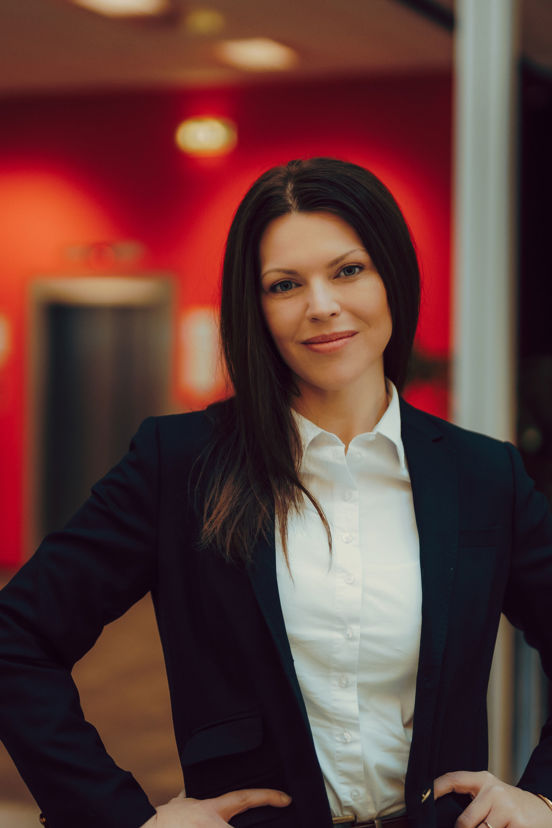 Portrett av Silje som står i et rom med røde vegger. 
