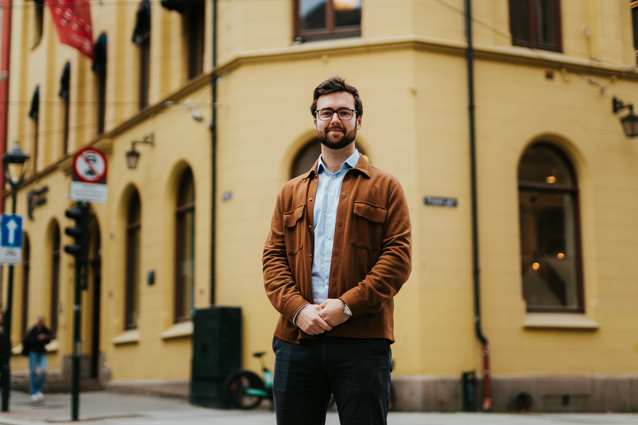 Kristiania-student Even Malmøy står utenfor ett av Kristianias bygg i kvadraturen. Han har armene foldet foran seg og smiler. Foto.