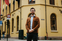 Kristiania-student Even Malmøy står utenfor ett av Kristianias bygg i kvadraturen. Han har armene foldet foran seg og smiler. Foto.