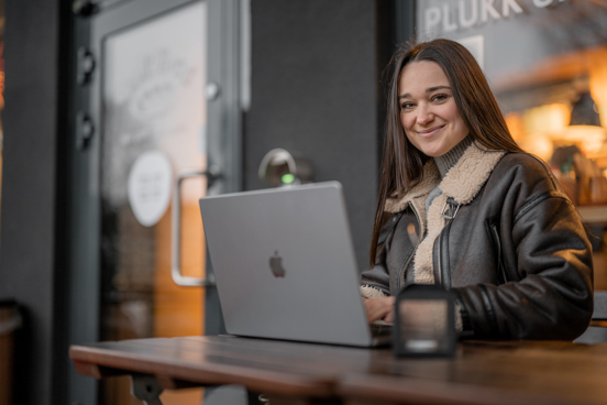 Student jobber på PC utenfor en kafé