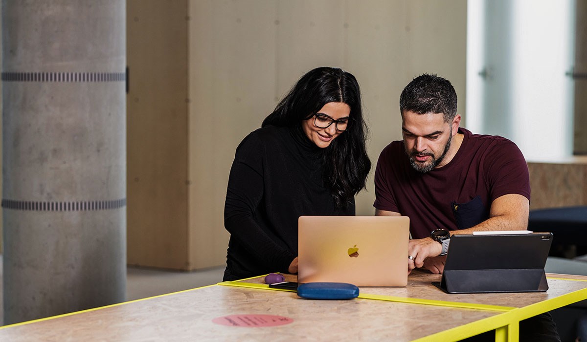 Kvinne og mann sitter foran en laptop og studerer