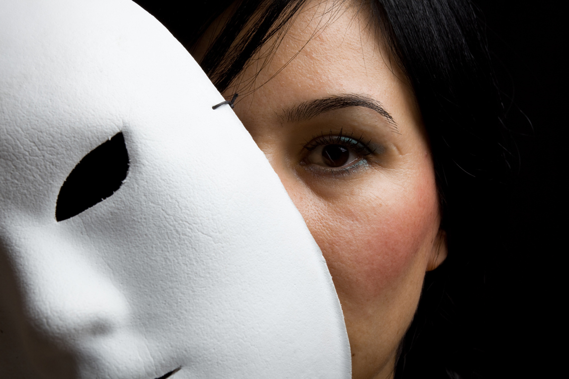 Kvinne med en hvit maske som dekker halve ansiktet.