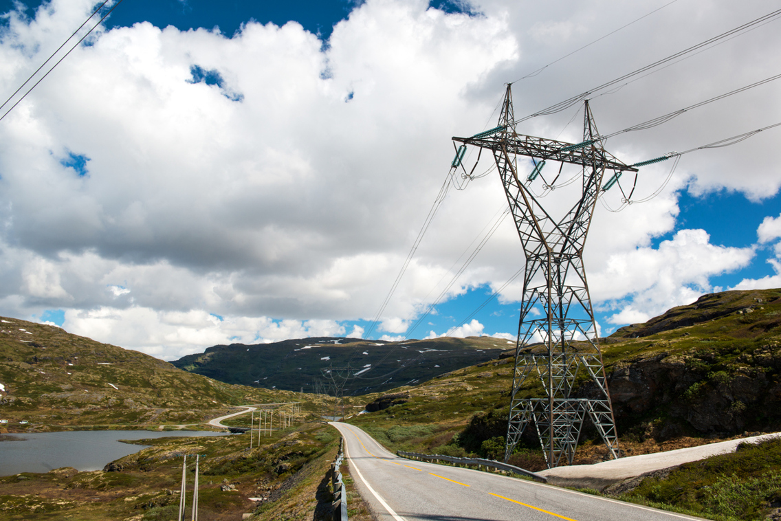 Høyspentmast og vei gjennom fjellandskap