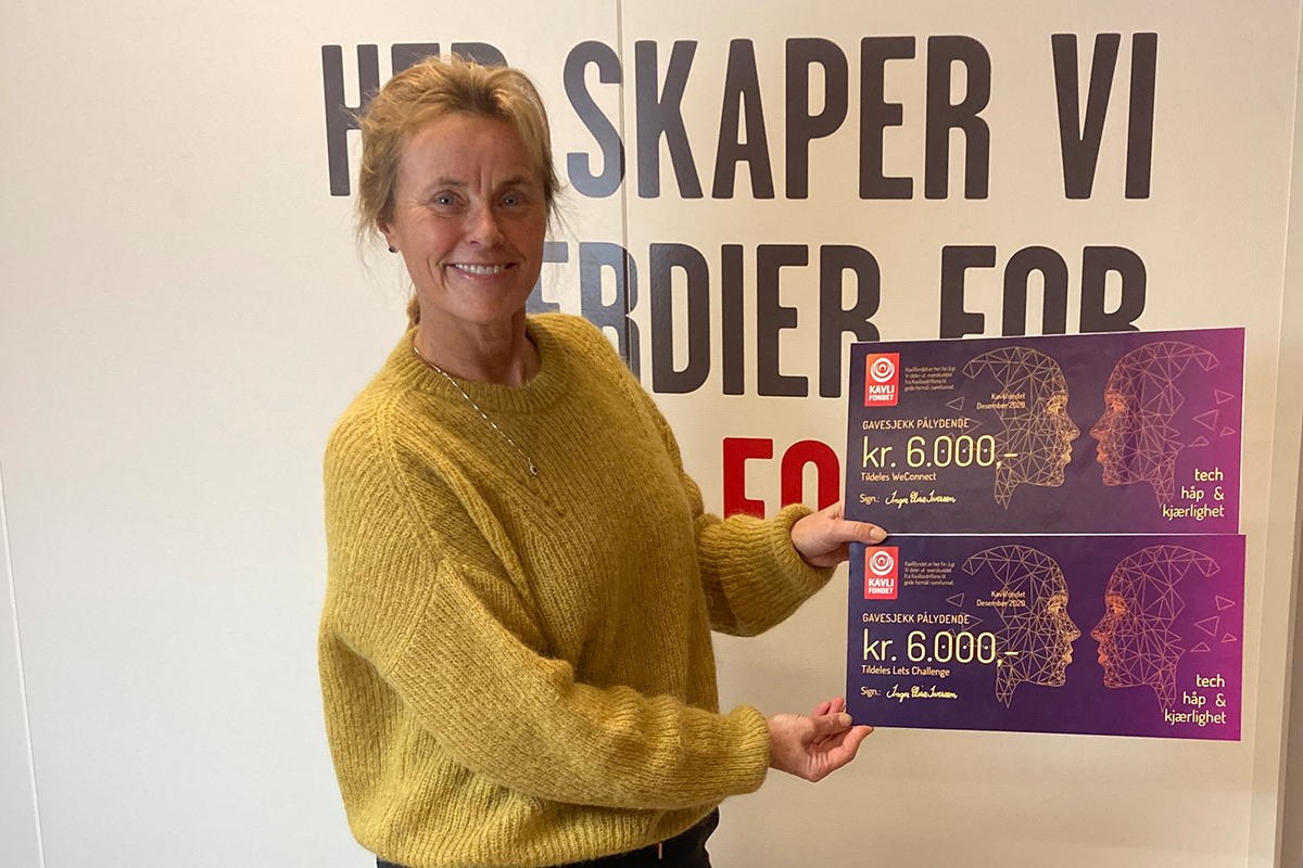 Kvinne står med to gavekort à 6000 kroner fra Kavlifondet.