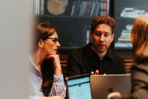 Tre mennesker jobber med PC på kontor i et møte.