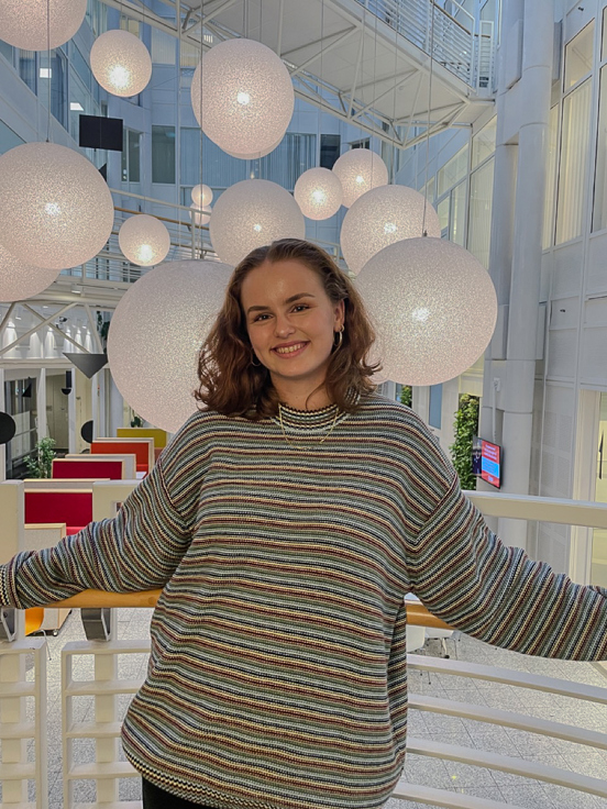 Cecilie Eike i trappen på Kristiania, med store lamper hengende i taket bak seg