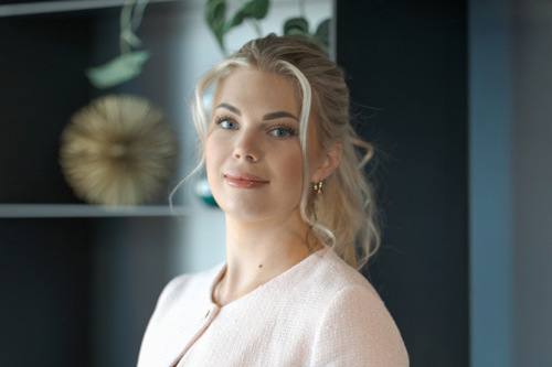 Portrett av Celine som ser inn i kamera, med sorte hyller i bakgrunnen.