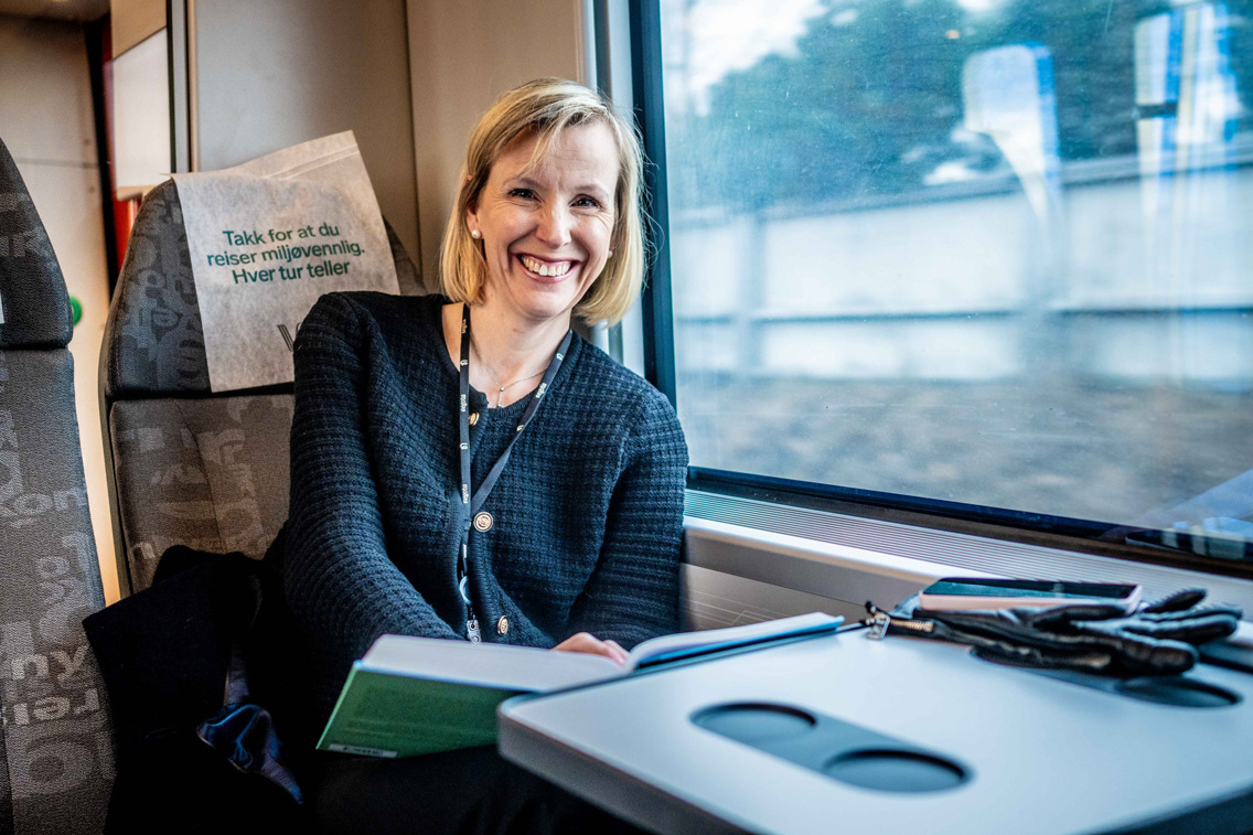 Kristine sitter på et tog og leser.