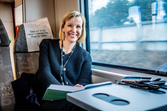 Kristine sitter på et tog og leser.