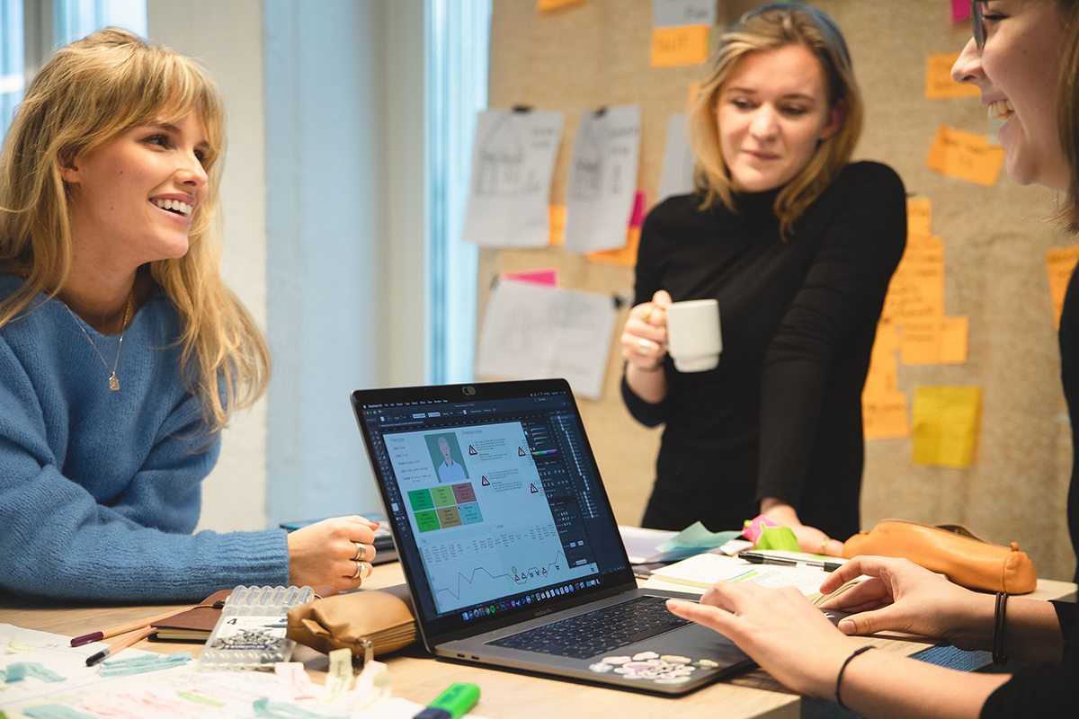 Studenter rundt en pc og skisser.