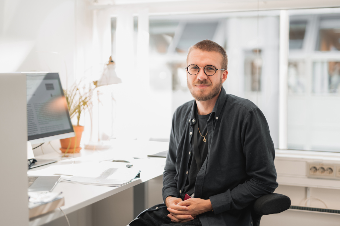 Foto av mann med briller foran skrivebord.