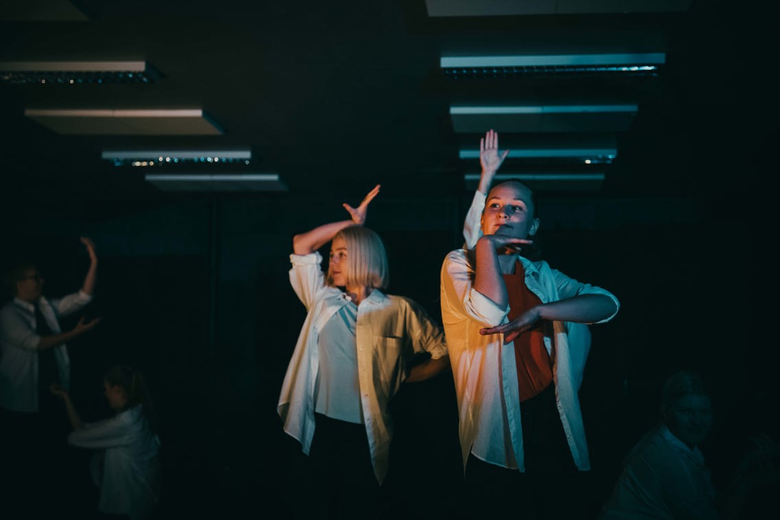 Bildet viser studenter på Bachelor i musikkteater på Høyskolen Kristiania. Dans og sang står i fokus på scenen i fargerik belysning.