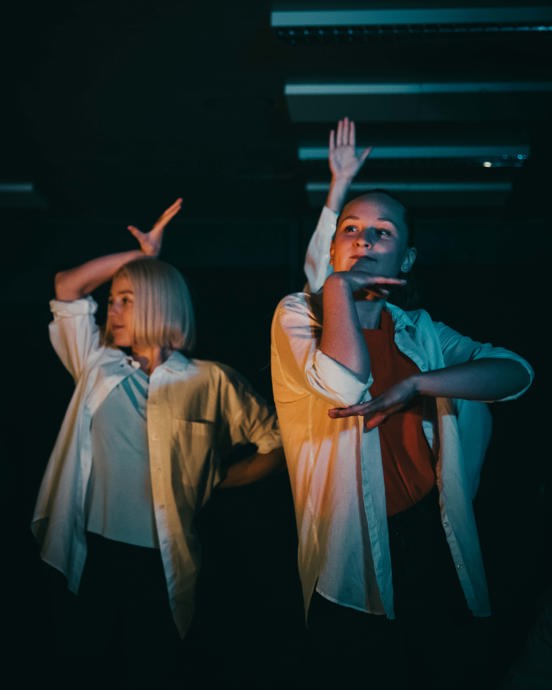 Bildet viser studenter på Bachelor i musikkteater på Høyskolen Kristiania. Dans og sang står i fokus på scenen i fargerik belysning.