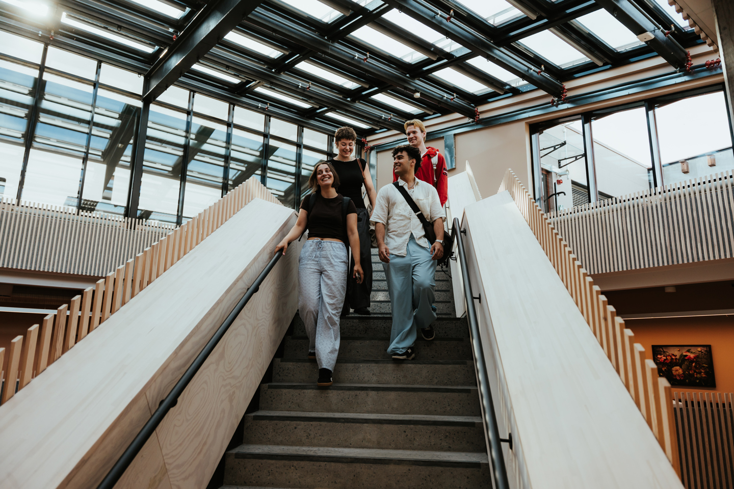 Studenter går ned trappa smilende på Kristiania.
