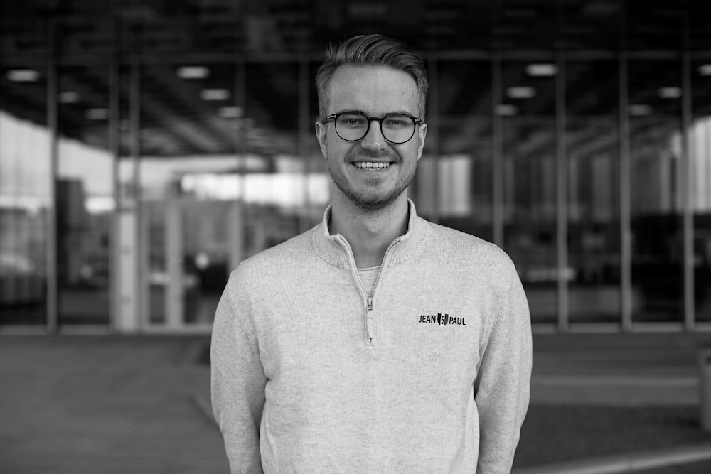 Foto av Håkon foran jobben sin i Flow Digital