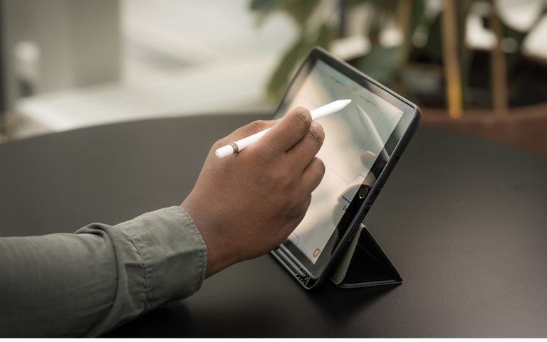 Hånd med penn som skriver noe på en Ipad