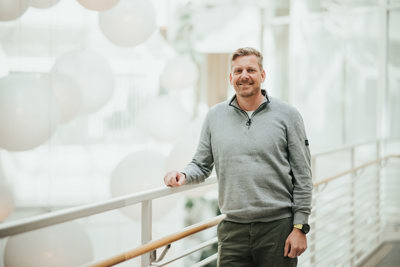 Mann i grå genser smiler til kamera.