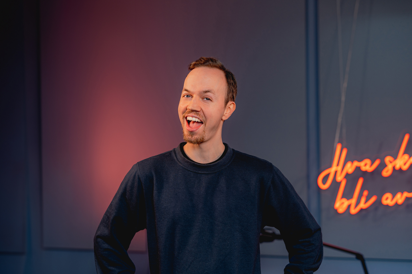 Aslak Maurstad står i podkaststudio og smiler til kamera.