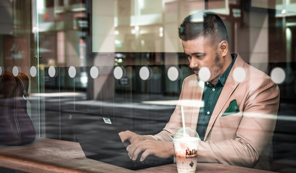 Foto av mann på kafé som jobber med en PC.