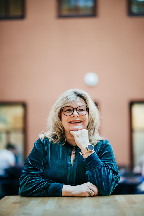 Trine Meza smiler rett mot kamera mens hun lener hodet på den ene hånden.
