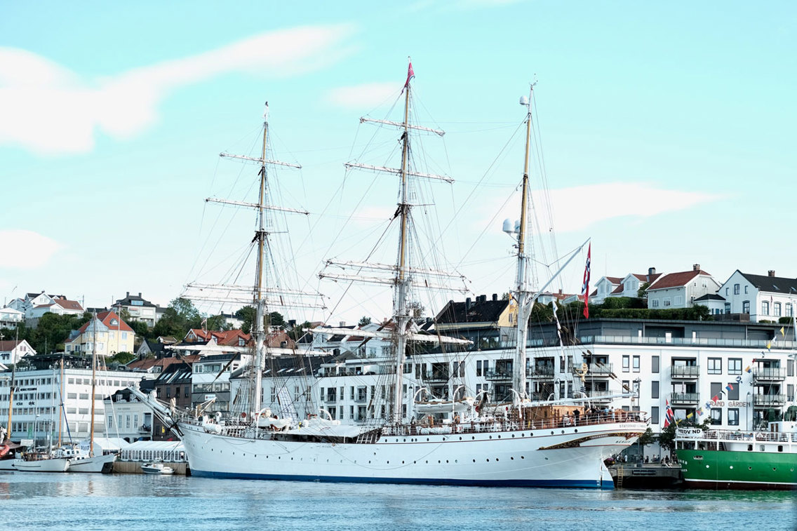 Gammelt seilskip ligger ved havn.