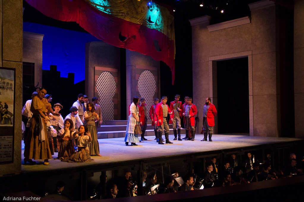 Two groups of people on a stage with orchestra underneath.