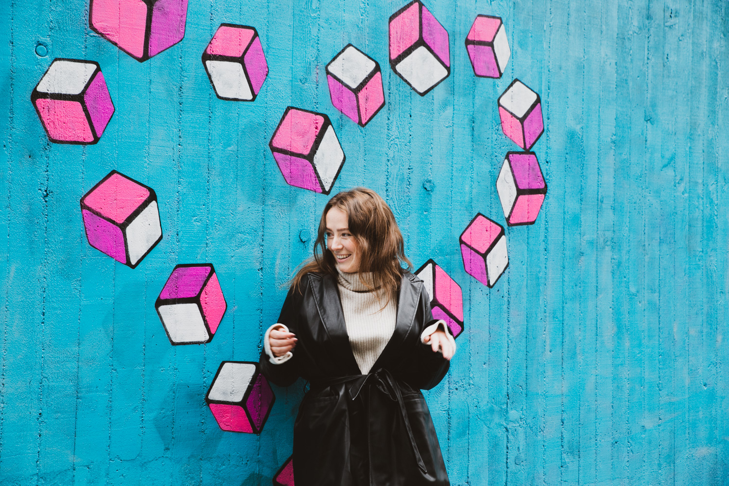 Maren står foran en grafittivegg med et rosa hjerte i bakgrunnen.  