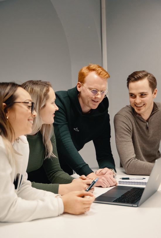 Foto av to mannlige og to kvinnelige studenter som ser på en PC.