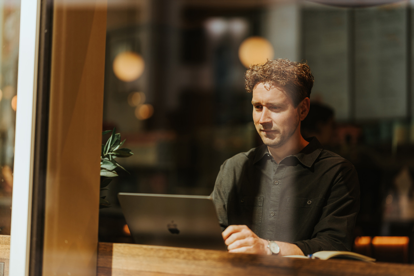 Mann jobber med PC på kafé.