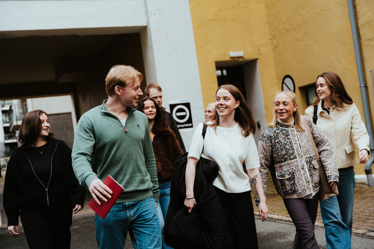 Studenter i Bergen går foran store murbygg.