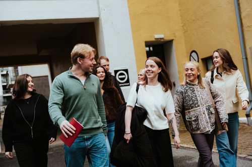 Studenter i Bergen går foran store murbygg.