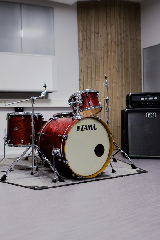 Trommer og bassforsterker i øvingsrom.