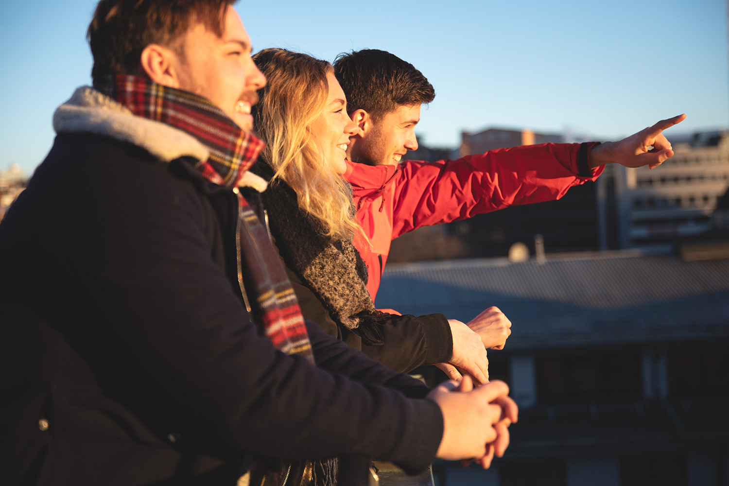 Foto av unge mennesker i vinterklær som peker utover et urbant syn.