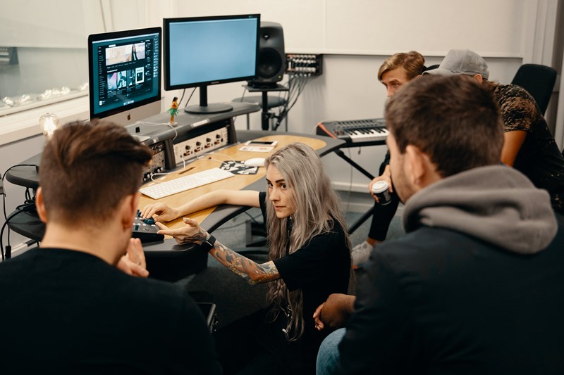 Gruppefoto av studenter i et lydstudio, foran en PC og et lydkort.