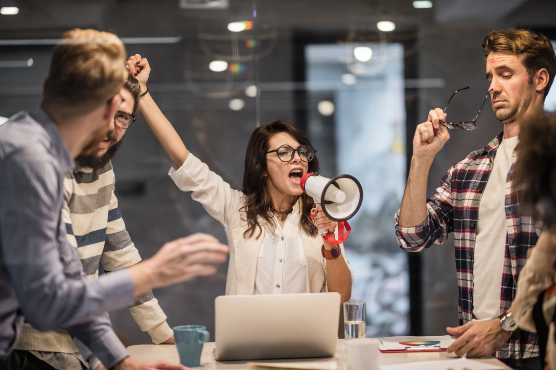 Woman talking loudly in a megaphone in a meeting with three other colleagues