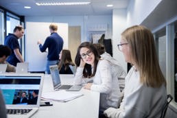 Foto av to kvinnelige studenter som sitter ved en laptop på et grupperom.