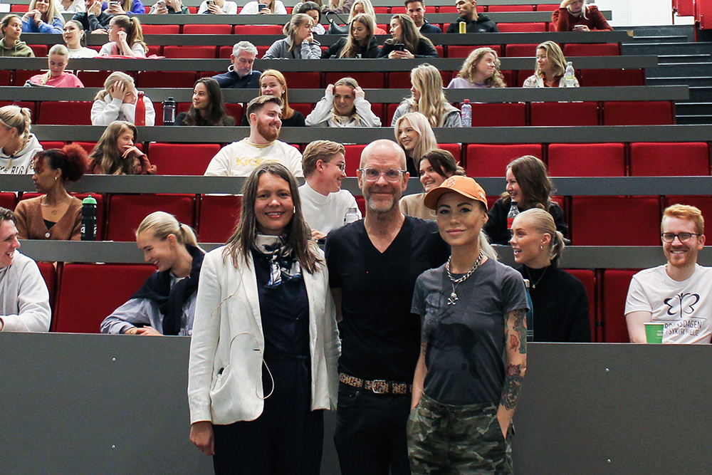 Tre personer foran publikum i auditorium.