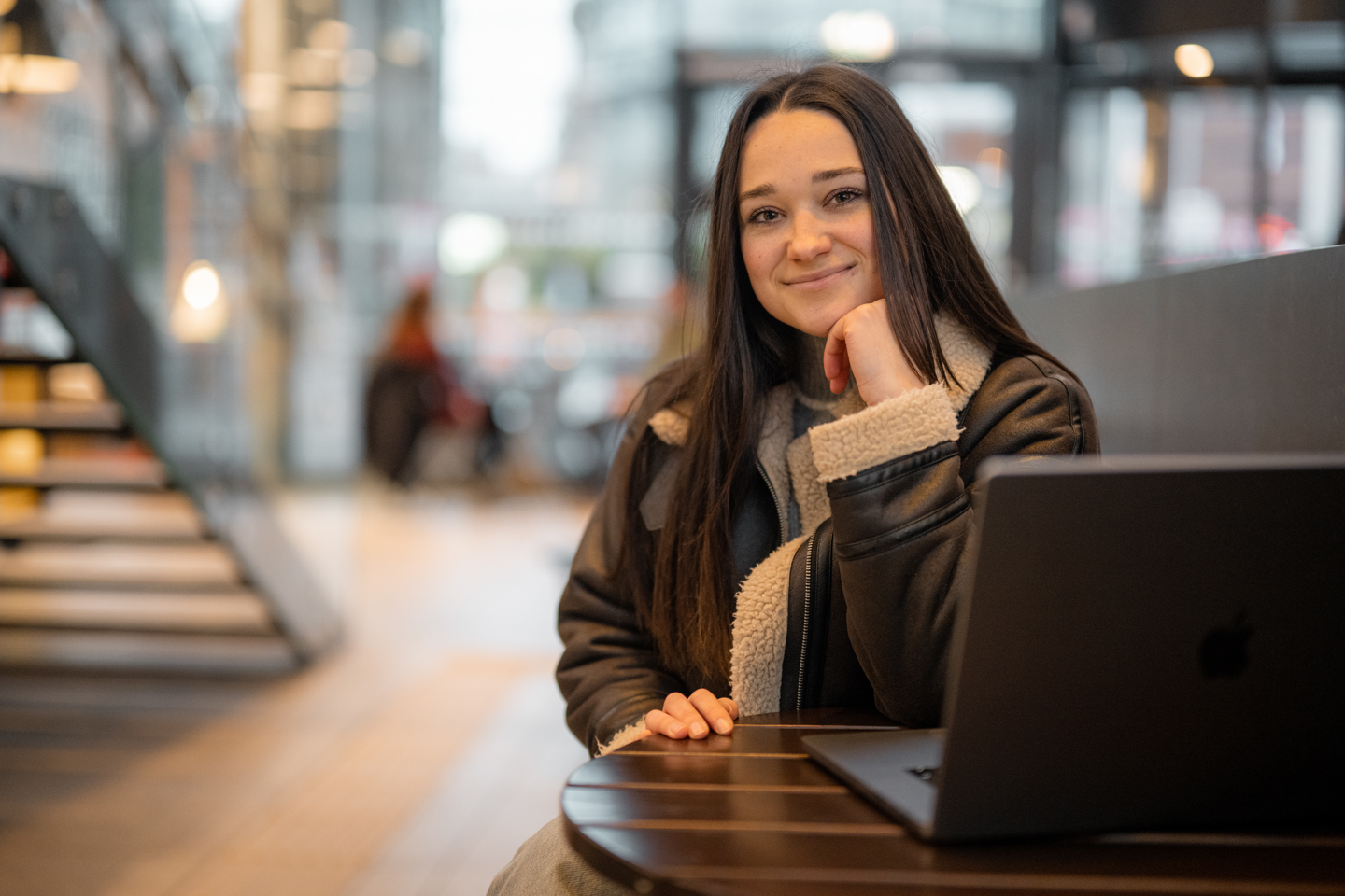 Person sitter ved et bord med en bærbar PC i et moderne innemiljø.