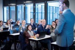 Foto av studenter som følger med på forelesning i et klasserom.