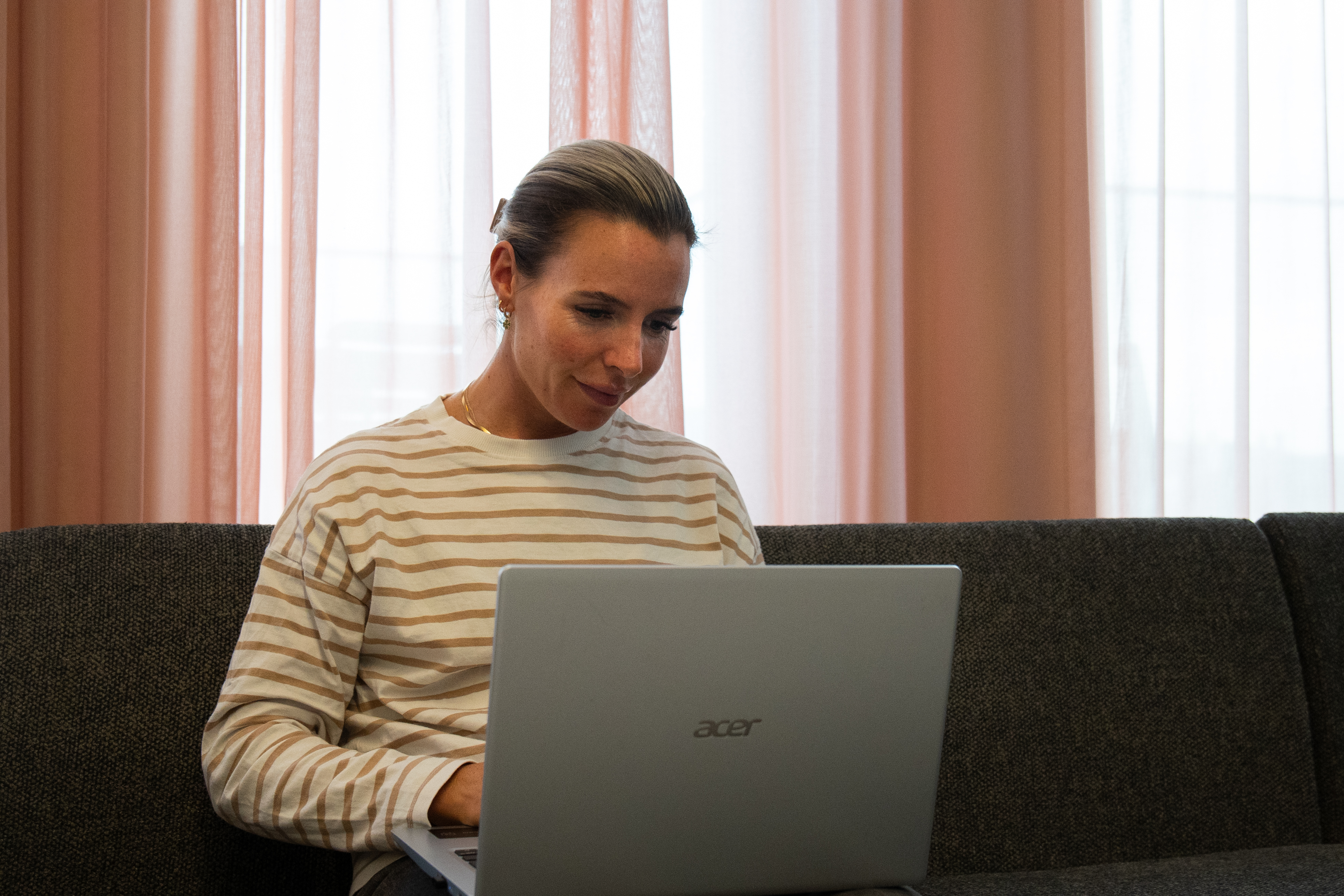 Christine jobber på en PC i en sofa