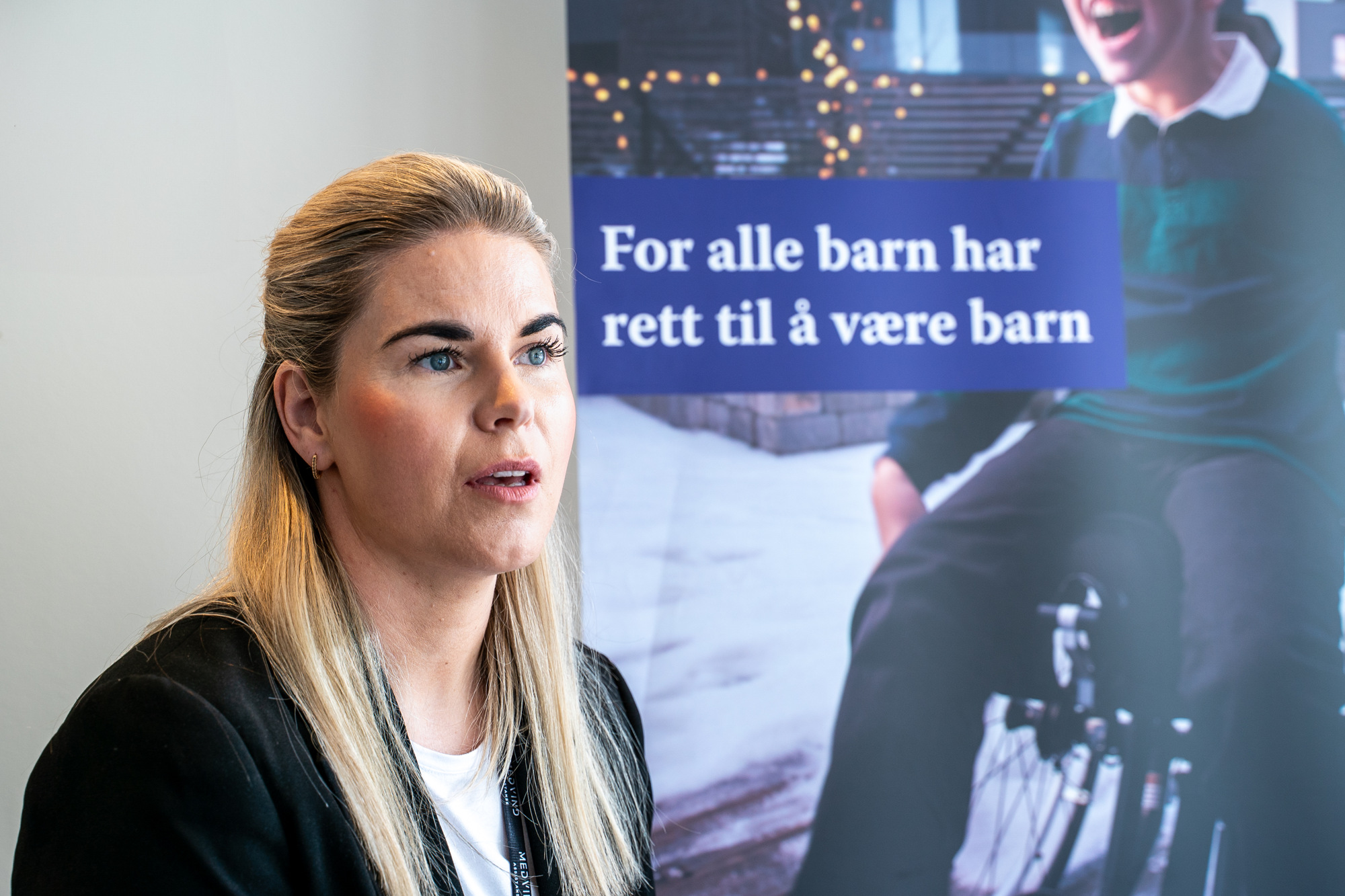 Ragnhild på kontoret med en plakat i bakgrunnen.