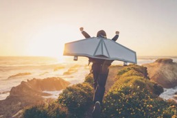 En person løper langs åskammen på et fjell i solnedgangen