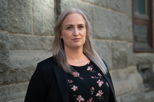 Foto av Malena foran en murvegg.