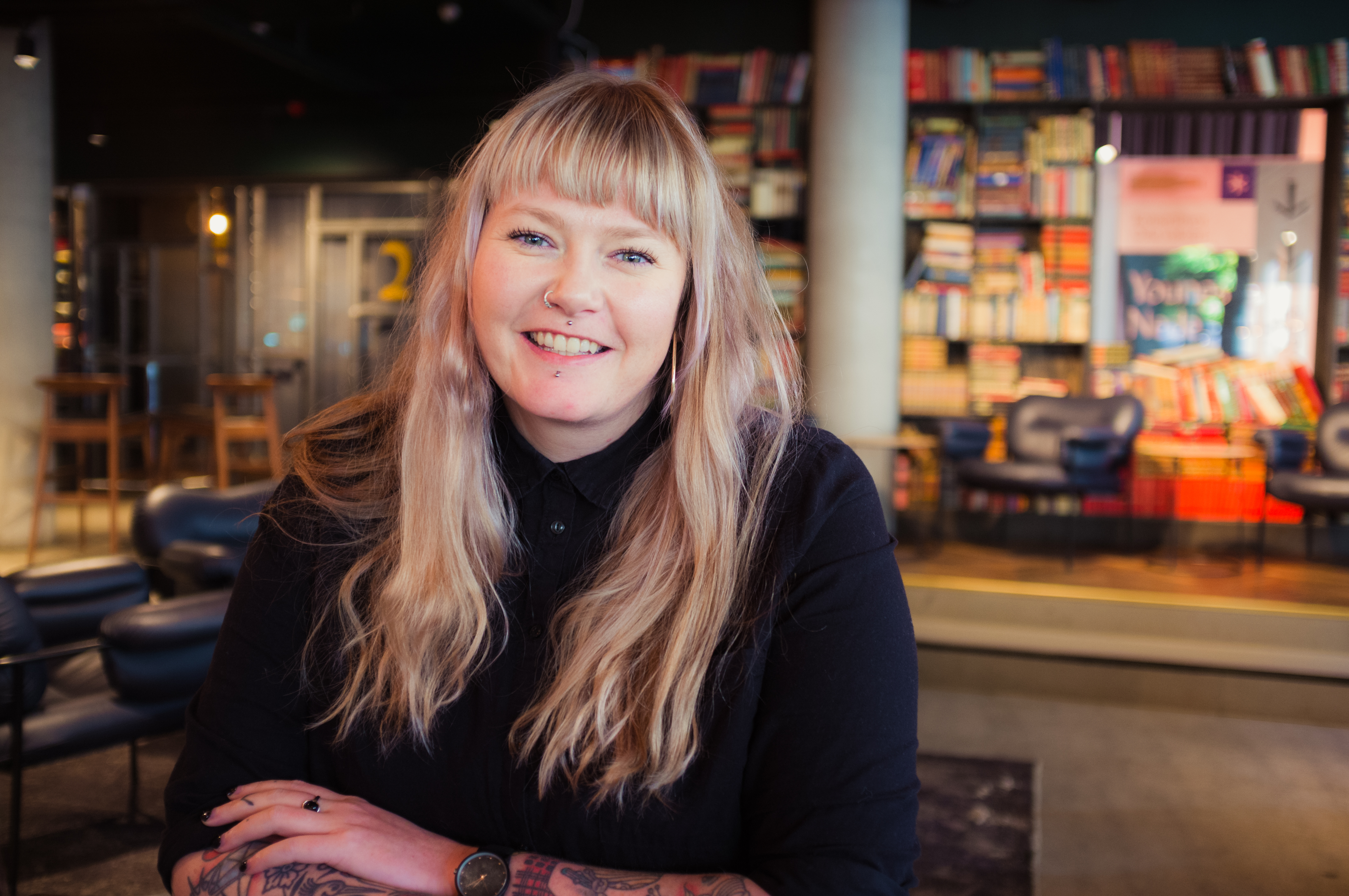 General Manager of Longyear United, Pernille Dragsten Holden is sitting by a table at Youngs in Oslo. She has long, blond hair, piercings and tattoos and is wearing a black shirt.