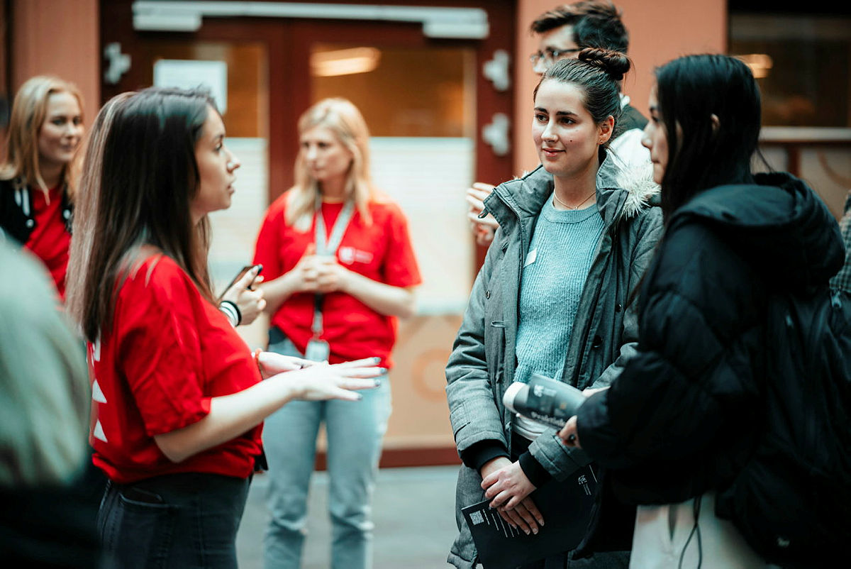 En studentambassadør snakker med to av de besøkende under Kristiania studiefestival.