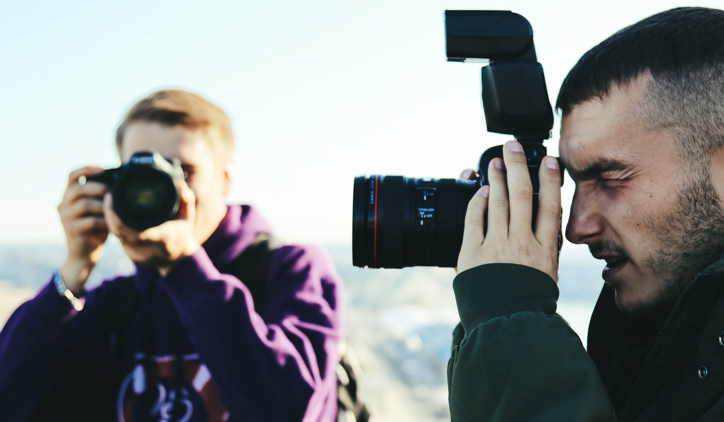 Bilde av to menn som holder hvert sitt kamera med natur i bakgrunnen