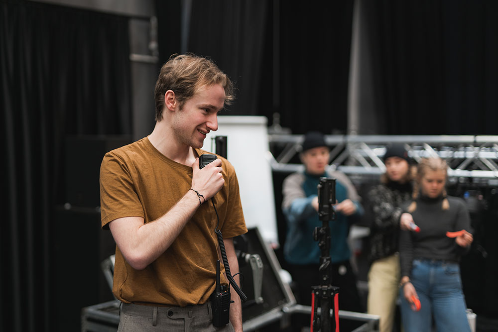 Foto av man med mikrofon som leder scenebyggingsarbeid.,