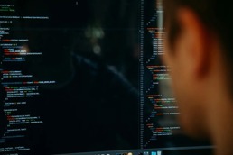 Person som sitter foran en pc-skjerm med et kode-program foran seg